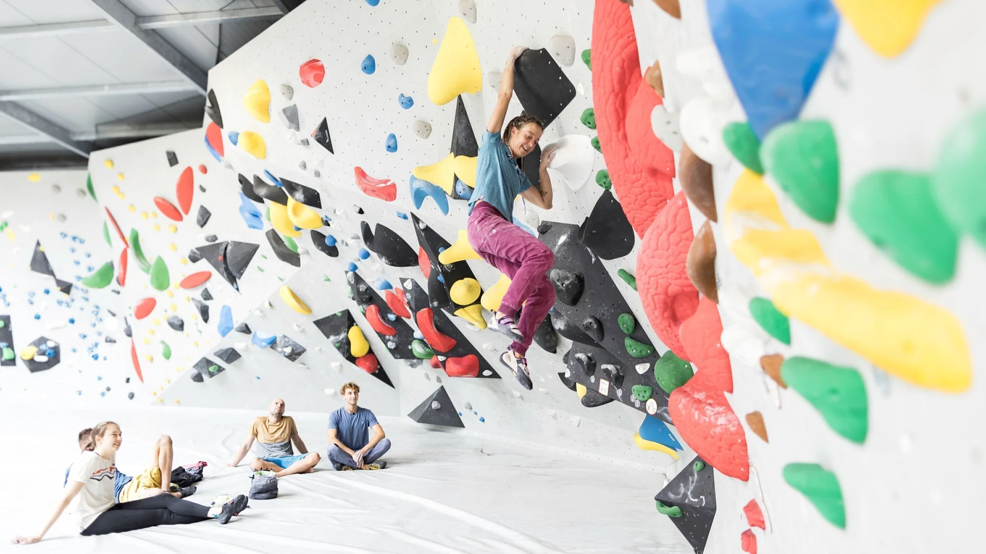 Eine Frau beim Bouldern, im Hintergrund warten weitere Personen, bis sie an der Reihe sind | © DAV / Jens Klatt