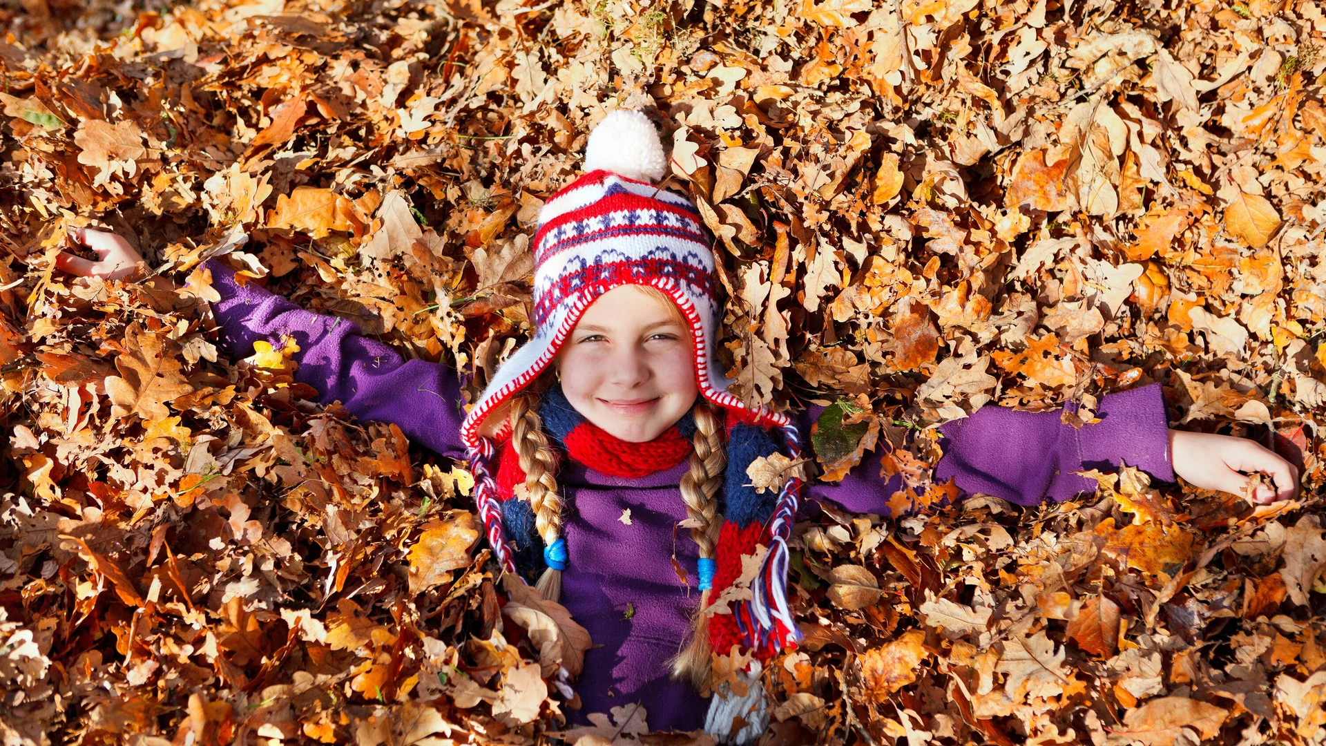 Ein Kind im Blätterhaufen bunter Herstblätter | © Ramona Heim